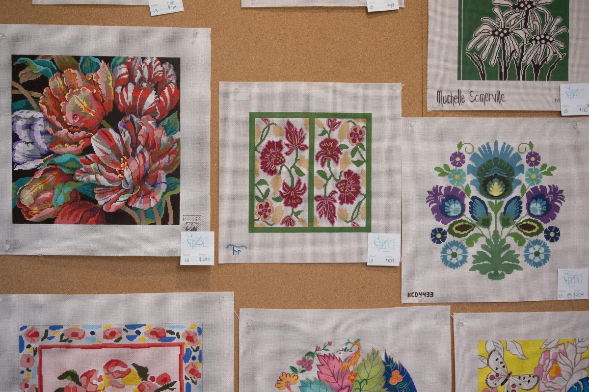 The walls of the Elegant Needle are lined with painted patterns for purchase, featuring various themes and colors.