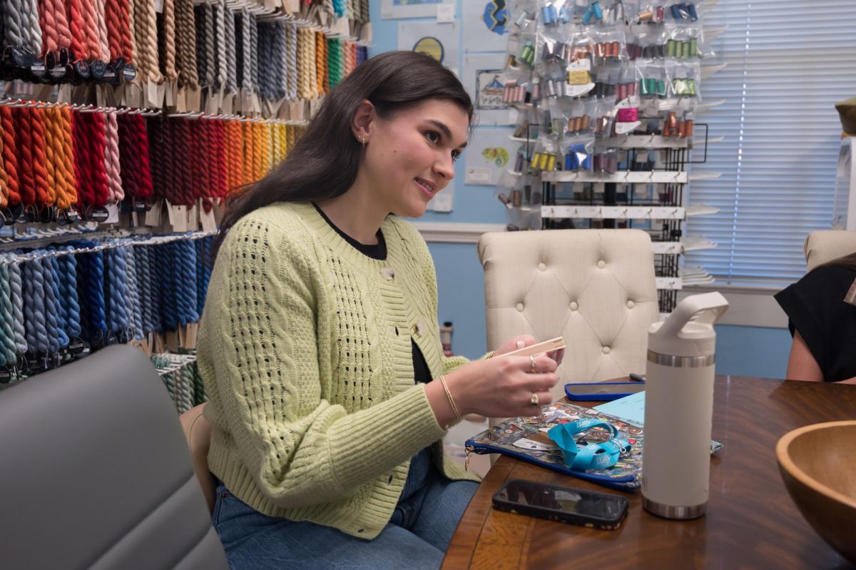Stitch Social BR co-creator Caroline Cantrelle works on her own project while sitting with other members, Monday, March 17, at the Elegant Needle.